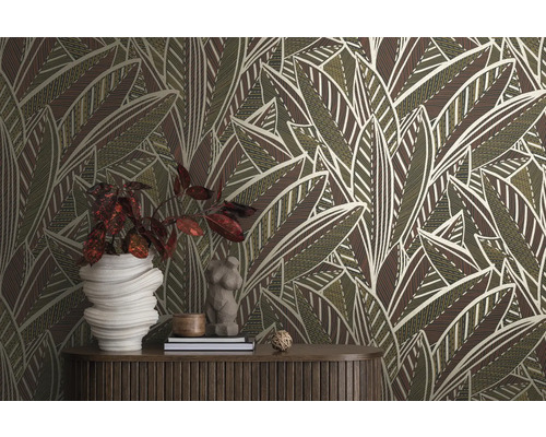 Raum mit einer Wandtapete mit Blattmuster, einem Holztisch und dekorativen Gegenständen.