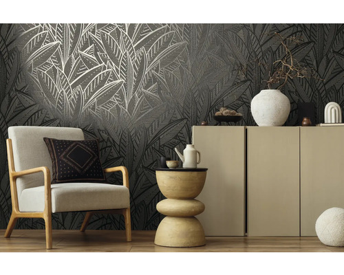 Wohnraum mit Sessel, Beistelltisch und Schrank vor einer gemusterten Tapete.