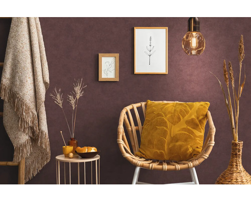 Wohnraum mit Rattansessel, Kissen, Beistelltisch, Dekoration und Wandbildern