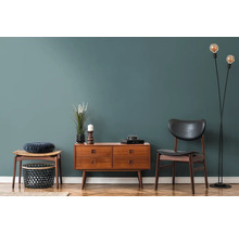 Wohnzimmer mit Holzkommode, Stuhl, Hocker und Stehlampe auf Parkettboden