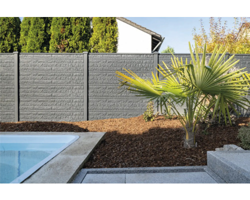 Graue Zaunanlage mit Mauerstruktur neben Pool und Palme