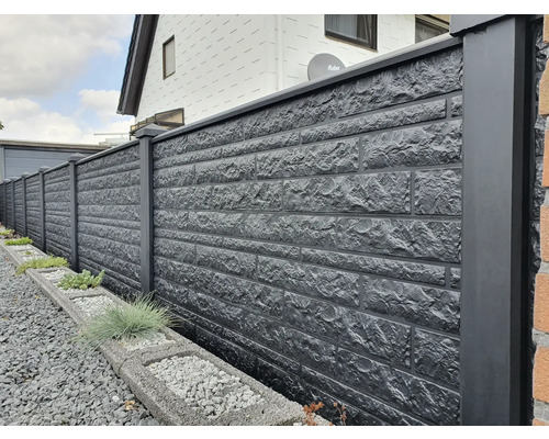 Eine lange, gemauerte Zaunanlage mit dunkelgrauen Säulen