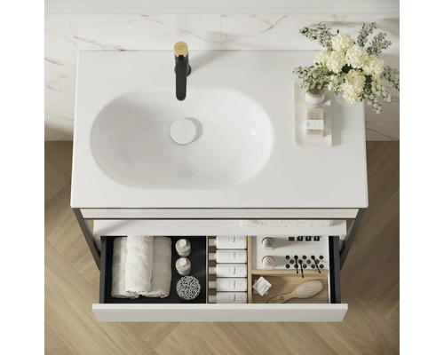 Blick von oben auf einen Waschtischunterschrank mit Waschbecken, Armatur und offenem Schubladenfach mit diversen Badutensilien.