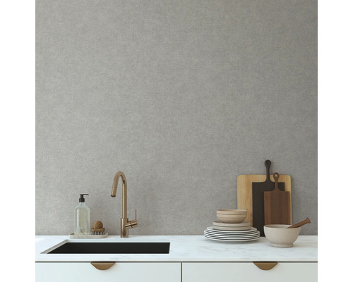 Küchenszene mit Spüle, Armatur, Geschirr und Schneidebrettern vor einer hellgrauen Wand