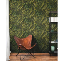 Raum mit Monstera-Blatt-Tapete, Ledersessel und Bücherregal