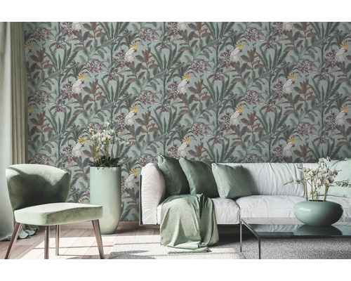 Wohnzimmer mit gemusterter Tapete mit Kakadu und Pflanzenmotiven, Sofa und Stuhl.