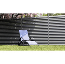 Gartenszene mit Loungesessel vor einem Lamellenzaun