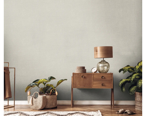 Szene mit einer Holzkommode, einer Lampe, Zimmerpflanzen und einer strukturierten Tapete