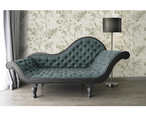 Chaiselongue mit Knopfheftung vor floral gemusterter Tapete und Stehlampe
