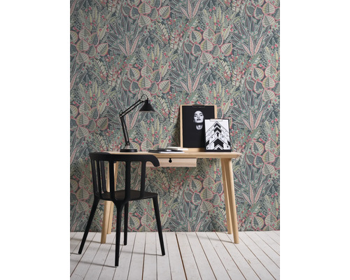 Ein Zimmer mit einem Schreibtisch, einem Stuhl und einer Tapete mit Pflanzenmuster.