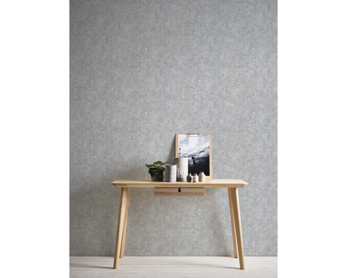 Szene mit einem Schreibtisch aus Holz vor einer grauen gemusterten Tapete.