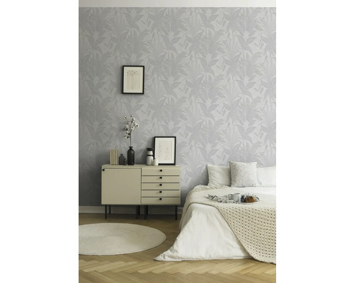 Helles Schlafzimmer mit gemusterter Tapete, Kommode, Bett und rundem Teppich