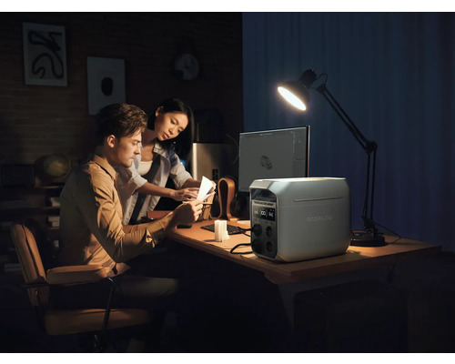 Ein Paar arbeitet an einem Schreibtisch mit einer EcoFlow Powerstation, einem Computer und einer Schreibtischlampe.
