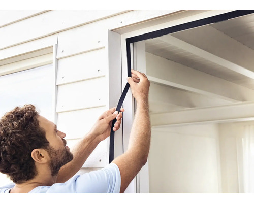 Eine Person befestigt eine Fensterdichtung an einem Fensterrahmen.