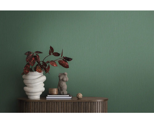 Dekorative Innenszene mit Pflanze in skulpturaler Vase, Frauenbüste und zwei Büchern auf einem braunen Schrank vor grüner Tapete