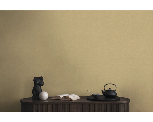 Dekorative Szene mit einer schwarzen Teekanne, einer Statue und einem Buch auf einem Schrank vor einer Wandtapete