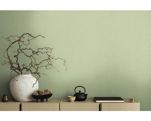 Dekorative Szene mit Vase, Ästen, Teekanne und weiteren Deko-Elementen auf einer Kommode vor einer Wand