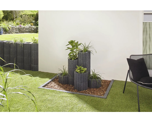 Gartenszene mit Pflanzsteinen in verschiedenen Größen und Bepflanzung auf Rasenfläche