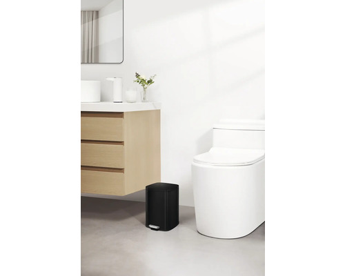 Badezimmer mit Toilette, Waschtisch und schwarzem Treteimer