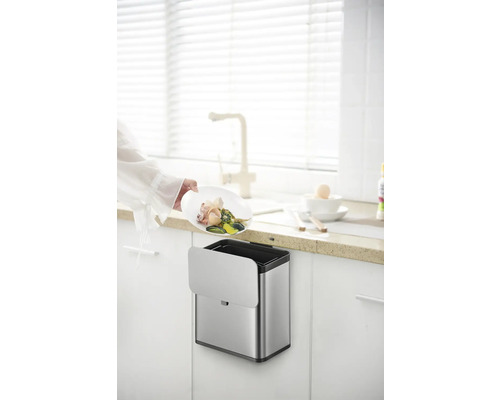 An der Schranktür montierter, silberfarbener Abfallbehälter mit Bioabfall