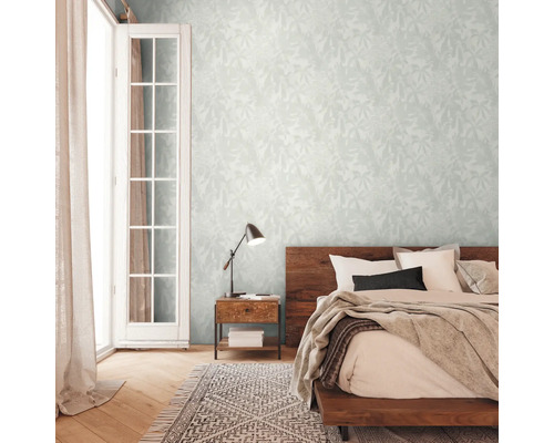 Schlafzimmer mit floral gemusterter Tapete, Bett, Nachttisch, Lampe und Teppich