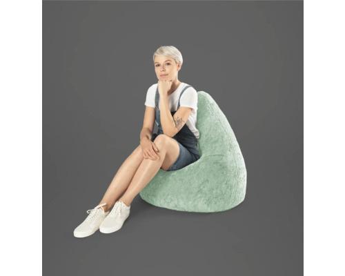 Frau sitzt auf einem tropfenförmigen Sitzsack aus Kunstfell