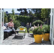 Terrasse mit Gartenmöbeln, Pflanzgefäßen und spielenden Kindern im Hintergrund