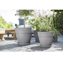 Blumenkübel aus Kunststoff mit Pflanzen auf einer Holzterrasse