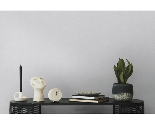 Dekoratives Arrangement mit Kerze, Skulptur, Uhr, Büchern und Topfpflanze auf einem schwarzen Tisch