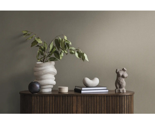 Dekoratives Arrangement auf einem Holzschrank mit einer gewundenen Vase, einer weiblichen Torsofigur und Büchern.