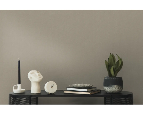 Dekoratives Wohnzimmerarrangement mit Kerze, Skulptur, Uhr, Büchern und Zimmerpflanze auf einem schwarzen Regal