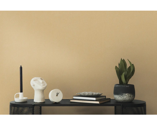 Dekorative Szene mit Kerze, Skulptur, Uhr, Büchern und Zimmerpflanze auf einem schwarzen Tisch