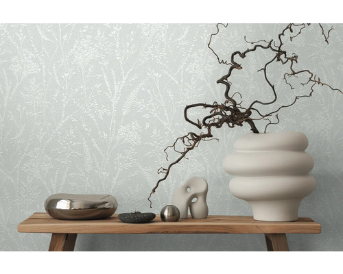 Dekoratives Stillleben mit floraler Tapete im Hintergrund, arrangiert auf einem Holztisch.