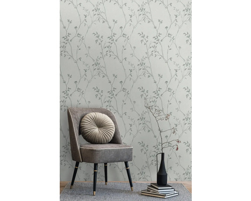 Tapete mit Blätterdesign im Interieur mit Stuhl, Kissen und Dekoration