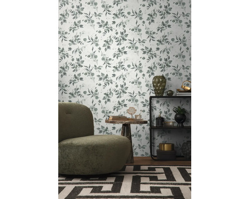 Dekoratives Zimmer mit Blättermuster-Tapete, Sessel, Regal und Teppich