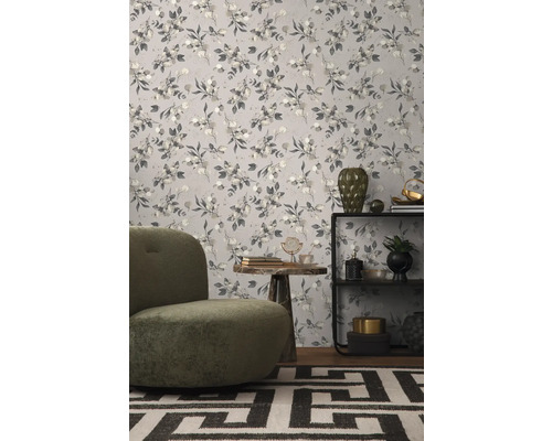 Raumansicht mit floral gemusterter Tapete, Sessel und Beistelltisch