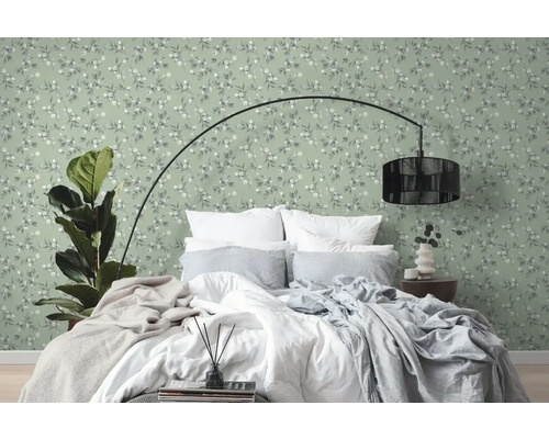 Schlafzimmer mit Bett vor grüner Wandtapete mit floralem Muster