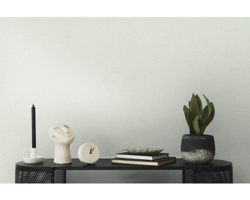 Dekoratives Arrangement auf einem schwarzen Tisch mit Kerze, Skulptur, Uhr, Büchern und Zimmerpflanze