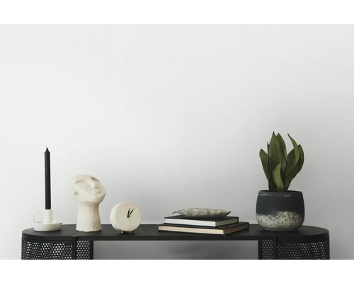 Dekorative Szene auf einem schwarzen Tisch mit Kerze, Skulptur, Uhr, Büchern und einer Zimmerpflanze