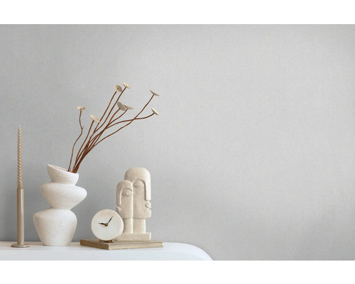 Dekorative Szene mit Vase, Blumen, Kerze, Uhr und Skulptur auf einem Tisch.