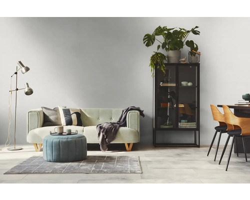 Wohnzimmer mit Sofa, Sessel, Stehlampe, Teppich, Vitrine, Tisch und Stühlen in einem hellen und modernen Design.