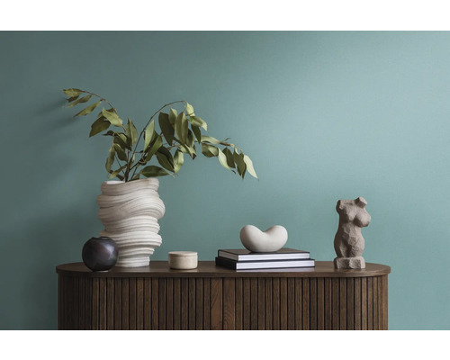 Dekorative Anordnung mit einer Vase, Büchern und einer Figur auf einem Holzschrank.