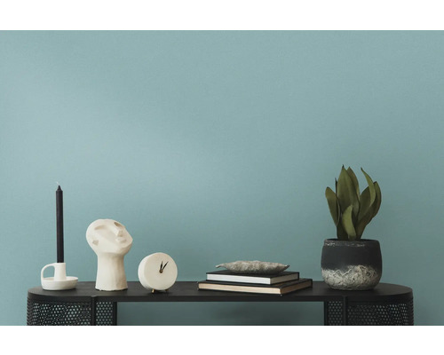 Dekorationsobjekte wie Kerze, Skulptur, Uhr, Bücher und Pflanze auf einem Tisch