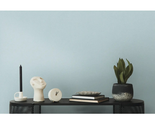 Dekorative Gegenstände wie Kerze, Skulptur, Uhr, Bücher und Zimmerpflanze auf einem Tisch