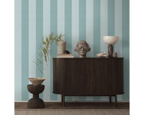 Wohnzimmer mit gestreifter Tapete, Sideboard und Dekorationsobjekten.
