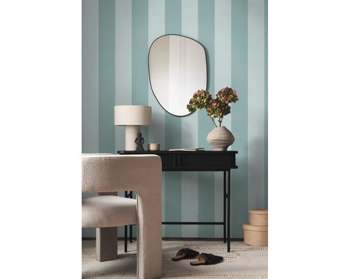 Einrichtungsgegenstände wie Spiegel, Tisch, Lampe, Dekoration und Stuhl vor einer blau-weiß gestreiften Wand.