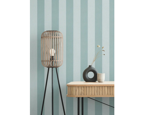 Zimmeransicht mit Stehlampe, Tisch und Dekoration vor gestreifter Tapete