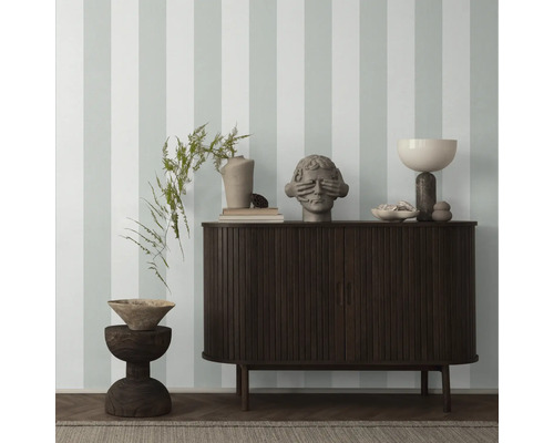 Interieur mit einem dunklen Holzschrank, Dekorationselementen und gestreifter Tapete.