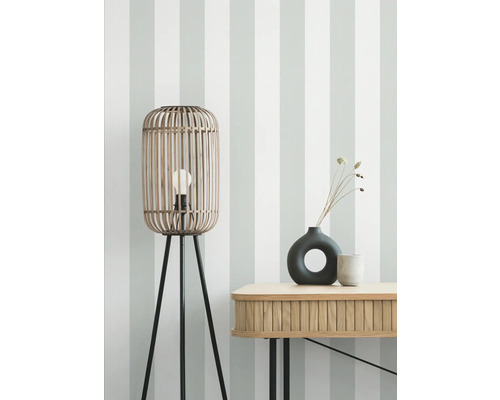 Stehlampe aus Bambus mit drei Beinen und Tisch mit Dekoration vor einer gestreiften Wand