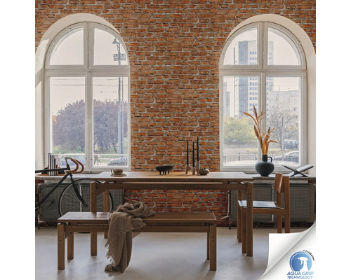 Esszimmer mit Holztisch, Bank und Stuhl vor einer Backsteinwand mit zwei großen Fenstern